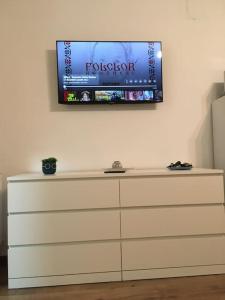 a flat screen tv on a wall above a dresser at Dbo-Vivo Mall Apartment in Baia Mare