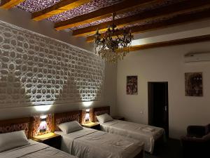 Habitación con 3 camas y lámpara de araña. en DOLON hotel, en Bukhara
