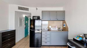 La cuisine est équipée d'un réfrigérateur en acier inoxydable et de placards blancs. dans l'établissement SureStay Studio by Best Western Virginia Beach Oceanfront, à Virginia Beach