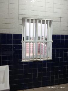 a window in a bathroom with blue tiles at Timba-Timbalog in Abomey-Calavi