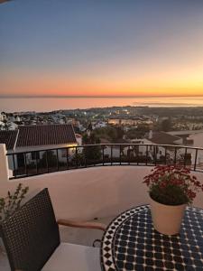 a table and chairs on a balcony with a sunset at CASA PERSEA in Nerja
