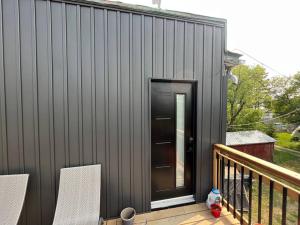a black house with a black door on a deck at Brand New Modern unit in town! in Cochrane