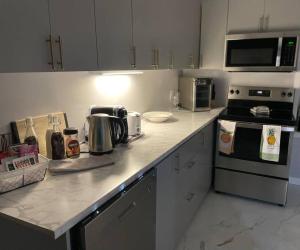 a kitchen with a counter top with a stove and microwave at Brand New Modern unit in town! in Cochrane