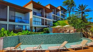 a resort with a swimming pool and chairs and a building at Diamond Flat in Morro de São Paulo