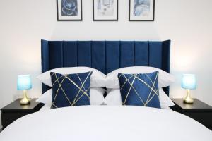 a bedroom with a blue headboard and two lamps at New Cardiff Bloc Exclusive Apartments By Prime Stays - Shops and Parking - Great for Groups and Families in Cardiff