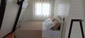 um pequeno quarto com uma cama e uma janela em Chale Brisa Do Mar em Palhoça