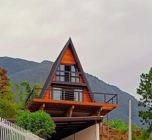 uma casa com um telhado de gambrel com uma varanda em Chale Brisa Do Mar em Palhoça