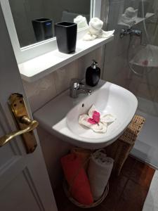 un lavabo blanco con una flor rosa. en Finca Mamposo, en Tacoronte