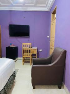 1 dormitorio con pared morada, sofá y TV en Heavens Gate, en Accra