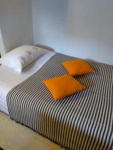 Apartment Marija Marina في مارينا: سرير ووسادتين برتقاليتين فوقه