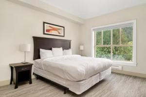a white bedroom with a large bed and a window at Harrison Lake Pets Welcome-3BR Penthouse Suite in Harrison Hot Springs