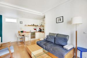 a living room with a blue couch and a kitchen at OBERKAMPF - MENILMONTANT Beatiful appartement for 2 peoples in Paris