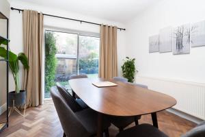 a dining room with a wooden table and chairs at Spacious London Haven for Family and Friends in London