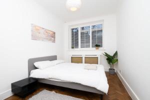 a white bedroom with a bed and a window at Spacious London Haven for Family and Friends in London