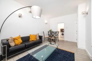 ein Wohnzimmer mit einem schwarzen Sofa und einem Tisch in der Unterkunft 2BR 2Baths ground floor garden apartment in Kingston upon Thames