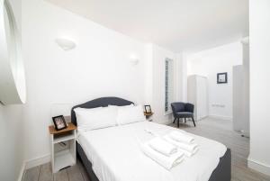 a white bedroom with a white bed and a chair at 2BR 2Baths ground floor garden apartment in Kingston upon Thames