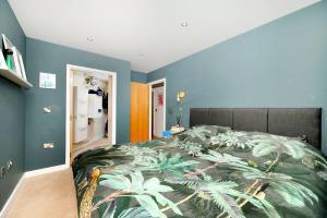 Cozy and modern 1BR flat in Enfield في انفيلد: غرفة نوم مع سرير مع طباعة استوائية عليه