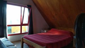 a bedroom with a red bed and a window at La Trunca Cabaña in Chascomús