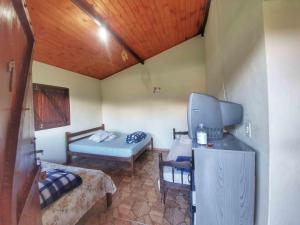 Habitación pequeña con cama y TV. en Chalé e Camping Elementais en São Tomé das Letras