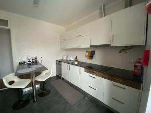 a kitchen with white cabinets and a table and chairs at Alojamento Quadros in Horta