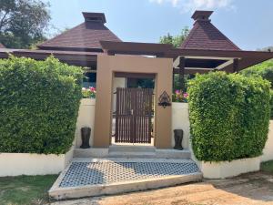 Kluai Mai Luxury Pool Villa, Panorama Resort في هوا هين: منزل فيه بوابة وشجيرتين