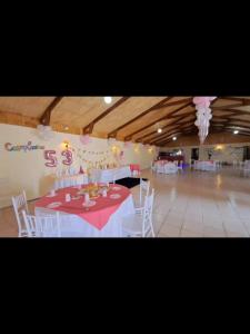 Zimmer mit einem Tisch mit weißen Stühlen und einem rosa Tischtuch in der Unterkunft HOSTAL EL AROMO pensión a empresas in Chillán