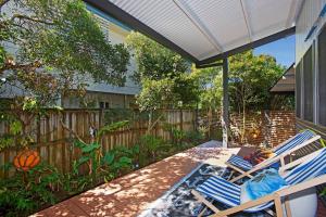 un patio avec deux chaises et une table et une clôture dans l'établissement Casuarina Cabana Beach House, à Casuarina