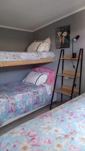 a bedroom with two bunk beds and a ladder at HOSTAL EL AROMO pensión a empresas in Chillán