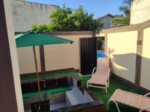 a patio with a table and an umbrella and a chair at Sobrado com hidromassagem in Cabo Frio