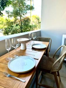 a wooden table with plates and wine glasses on it at Luxury 1 BR Apartment in Randwick- Walk to hospital UNSW Dining W parking and lift and AC in Sydney +17 photos