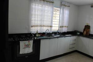 uma cozinha com armários brancos, um lavatório e um fogão em Chácara da Bia em Várzea Paulista