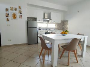 uma cozinha branca com uma mesa e cadeiras brancas em Serao House, 2 piano in centro em Mondragone