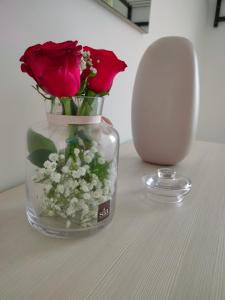 um vaso com rosas vermelhas e flores brancas sobre uma mesa em Serao House, 2 piano in centro em Mondragone