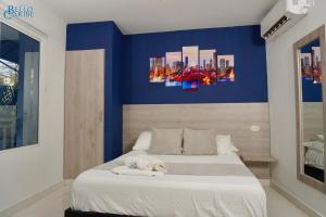 1 dormitorio con 1 cama grande y paredes azules en Hotel Bello Caribe en Santa Marta