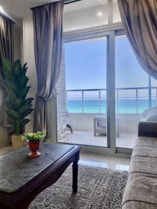 a living room with a table and a view of the ocean at Alexandria Luxury Apartments Sporting Direct Sea View in Alexandria