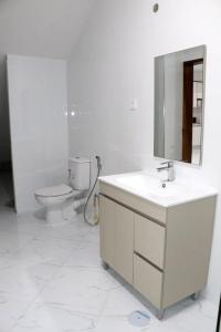a white bathroom with a sink and a toilet at Figo Apartamentos in Praia