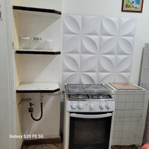 a small kitchen with a stove and a shelf at Apto no Embaré pé na areia in Santos