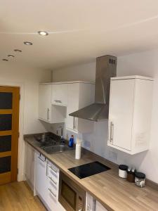 a kitchen with white cabinets and a stove top oven at Studio apartment near Sutton, Croydon in Banstead