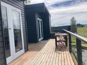 una terrazza in legno con tavolo e sedia di Hayshed Cabins - Merigan Farm Stay a Tarago