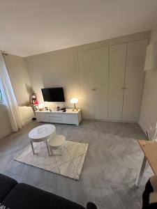 a living room with a table and a tv at Studio Villennes sur seine cosy Paris Versailles in Villennes-sur-Seine