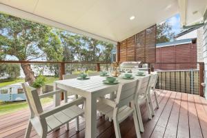 a dining room with a table and chairs on a deck at Aqua by Experience Jervis Bay in Sanctuary Point