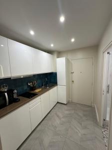 a kitchen with white cabinets and a tile floor at Studio Villennes sur seine cosy Paris Versailles in Villennes-sur-Seine