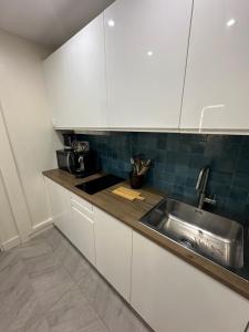 a kitchen with white cabinets and a sink at Studio Villennes sur seine cosy Paris Versailles in Villennes-sur-Seine +1 photo