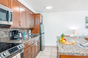 a kitchen with wooden cabinets and a counter with fruit on it at Waikiki Banyan 15FL - views, pool & hot tub access in Honolulu