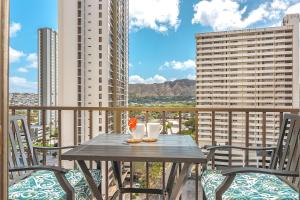 einen Tisch und Stühle auf einem Balkon mit Gebäuden in der Unterkunft Diamond Head View Condo, Steps to Beach & Free Parking! in Honolulu
