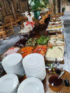 a buffet of food with white plates on a table at Hotel Fazenda Rancho Grande in Linha Blinda