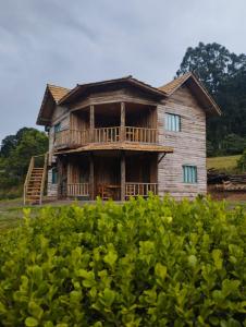 an old wooden house with a deck in a field at Hotel Fazenda Rancho Grande in Linha Blinda