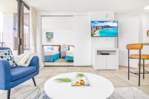 ein Wohnzimmer mit einem blauen Stuhl und einem Tisch in der Unterkunft Diamond Head View Condo, Steps to Beach & Free Parking! in Honolulu