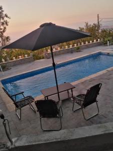 a table and chairs with an umbrella next to a swimming pool at Villa de campagne dans les hauteurs, vue panoramique sur mer in Ghazaouet