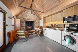 eine Küche mit einer Waschmaschine, einem Trockner und einem Steinkamin in der Unterkunft The Stone Cottage at Wollondibby - Heritage Listed l Renovated l Fire Place in Crackenback + 20 Fotos